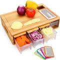 Bamboo cutting board with drawers containing sliced vegetables and a grater on a white background