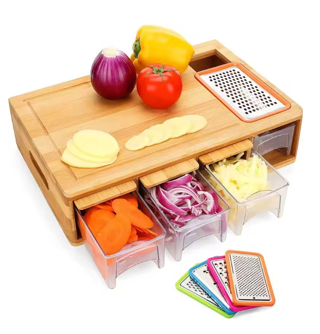 Bamboo cutting board with drawers, grater, and vegetables on a white background