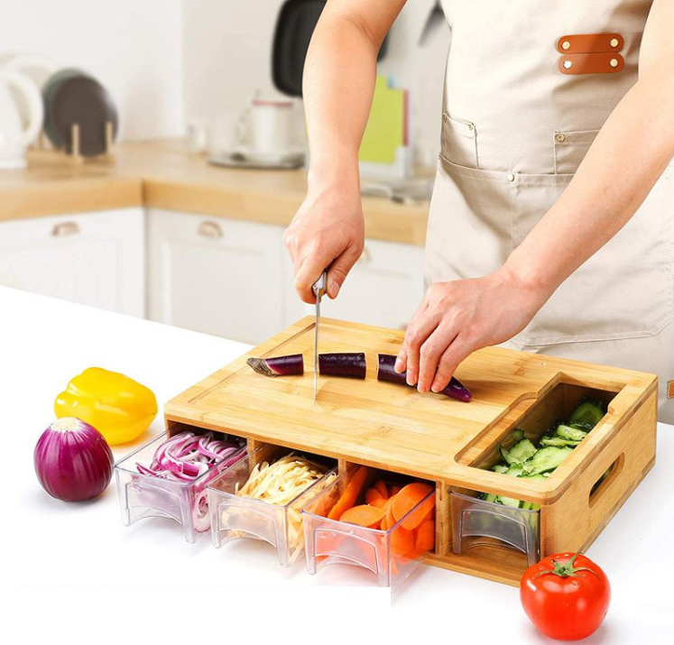 Person using a bamboo cutting board with compartments in a kitchen.